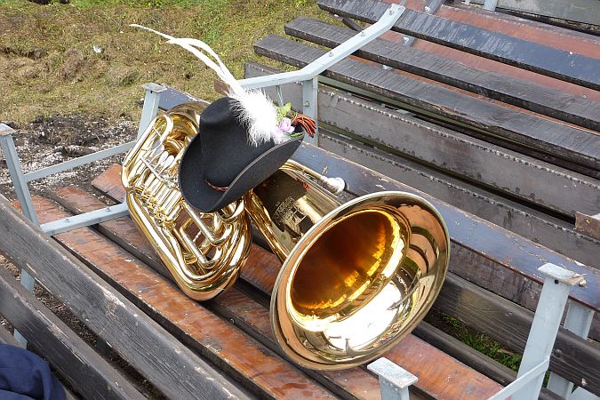 eine Holzbank, darauf eine riesige Tuba und auf dieser ein Hut eines Musikanten der Musikkapelle